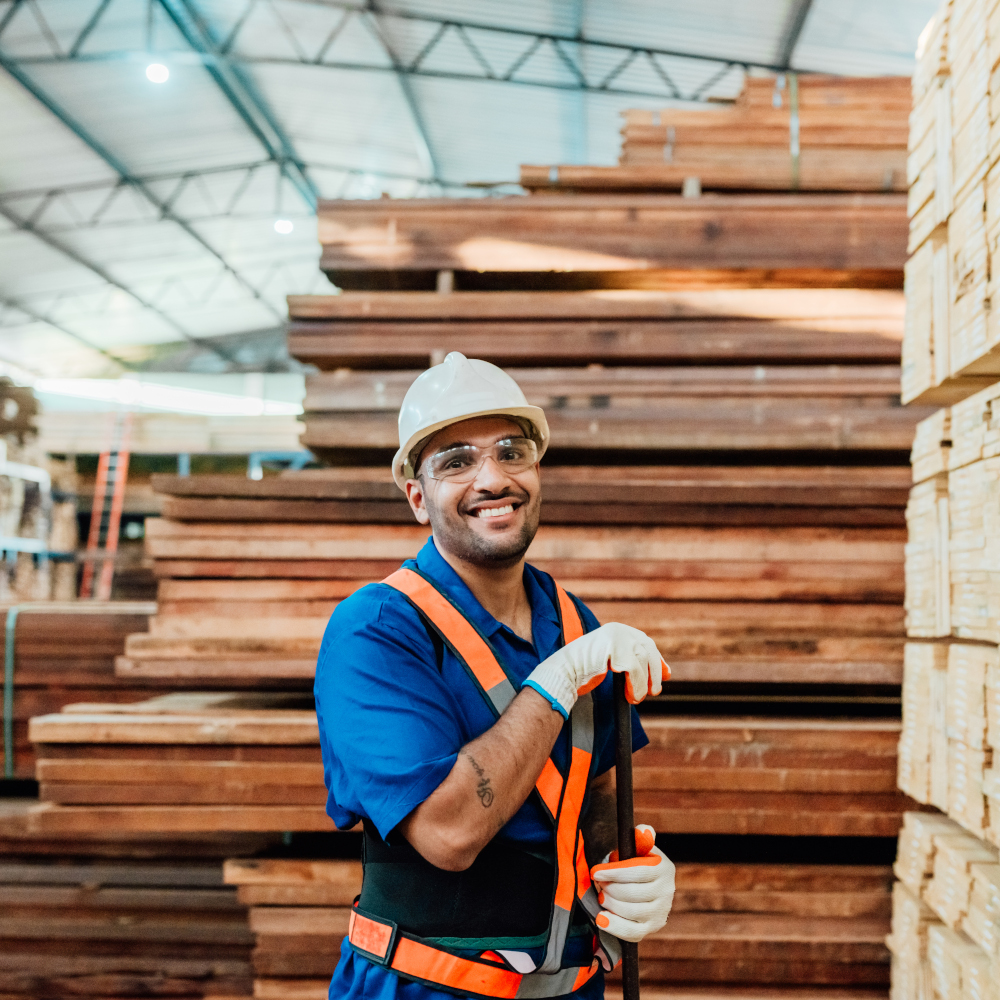 Worker smiles in front of pallet of wood