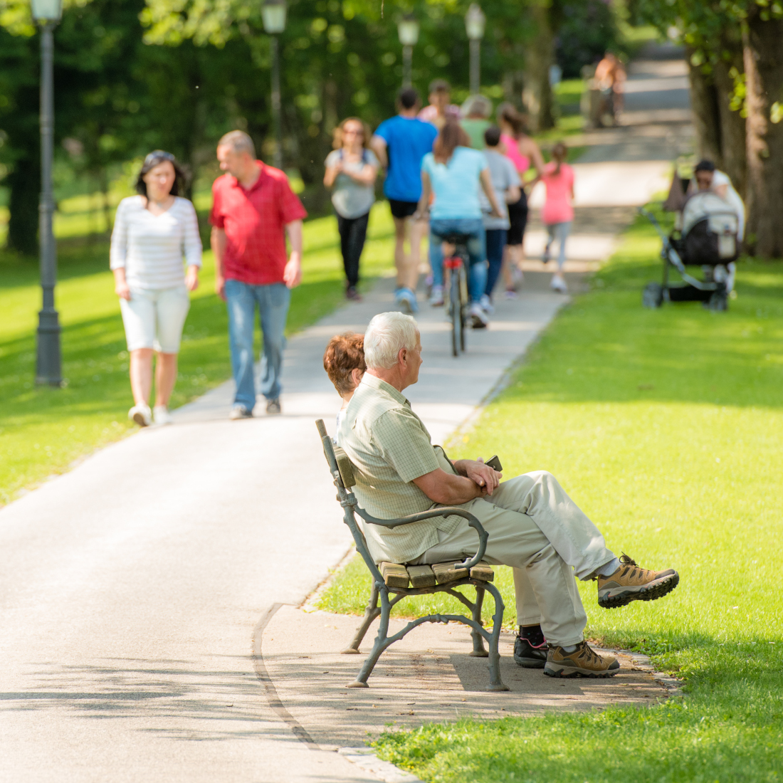 Couple sits at bench while others pass